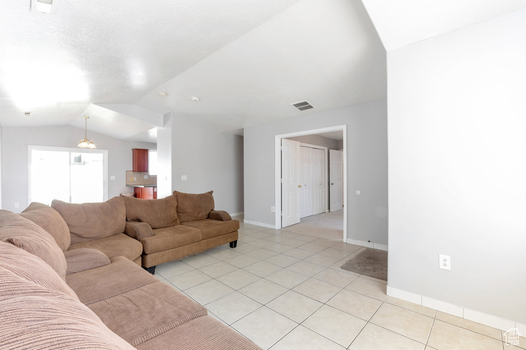 Living room featuring light tile patterned flooring, vaulted ceiling, baseboards, and visible vents