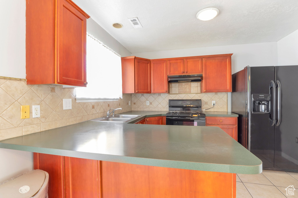 Kitchen featuring under cabinet range hood, visible vents, a sink, a peninsula, and black appliances