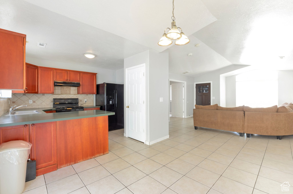 Kitchen with under cabinet range hood, light tile patterned floors, a sink, open floor plan, and black appliances