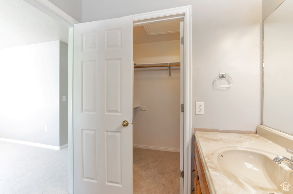 Bathroom featuring vanity, a spacious closet, and baseboards