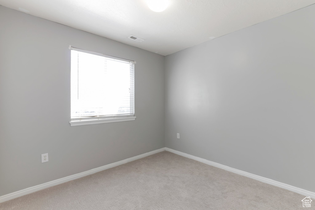 Unfurnished room featuring light colored carpet, visible vents, and baseboards