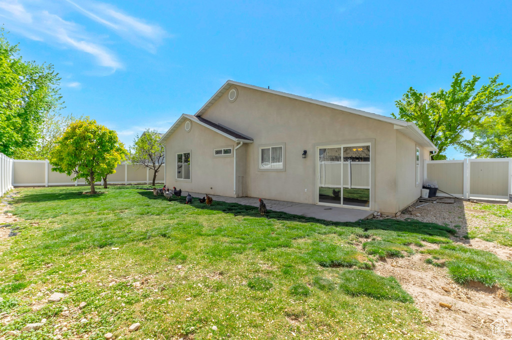 Rear view of house with a yard, a patio area, stucco siding, and a fenced backyard