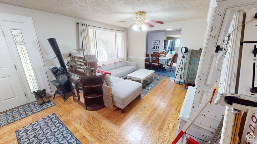 Living area featuring ceiling fan, a textured ceiling, and wood finished floors