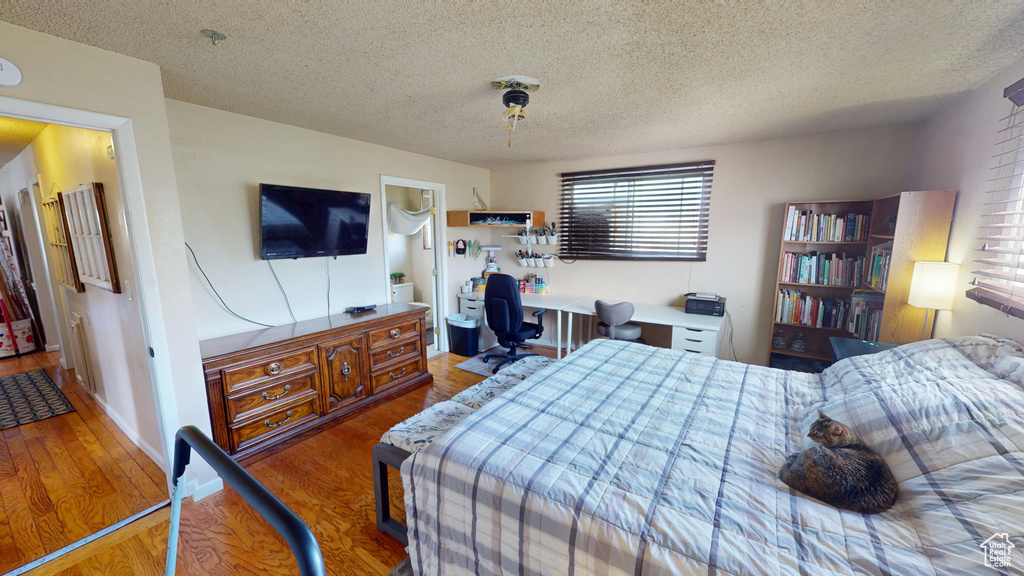 Bedroom featuring multiple windows, a textured ceiling, and wood finished floors