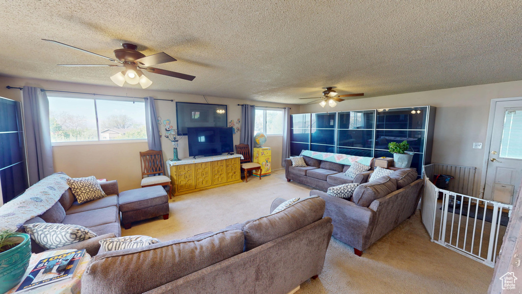 Living room featuring ceiling fan, light carpet, and a textured ceiling