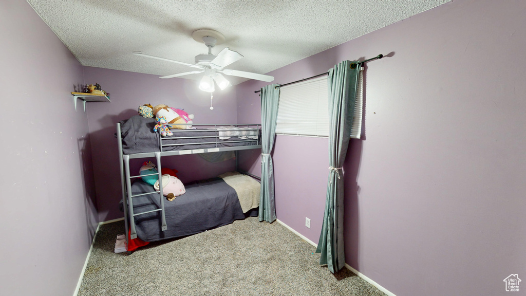 Carpeted bedroom with a textured ceiling and a ceiling fan