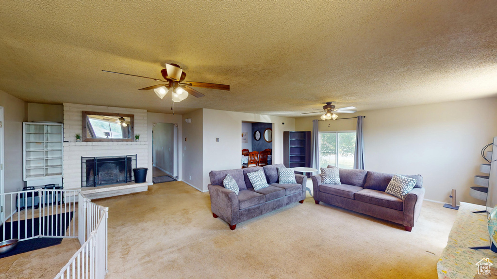 Carpeted living room with a ceiling fan, a textured ceiling, and a fireplace