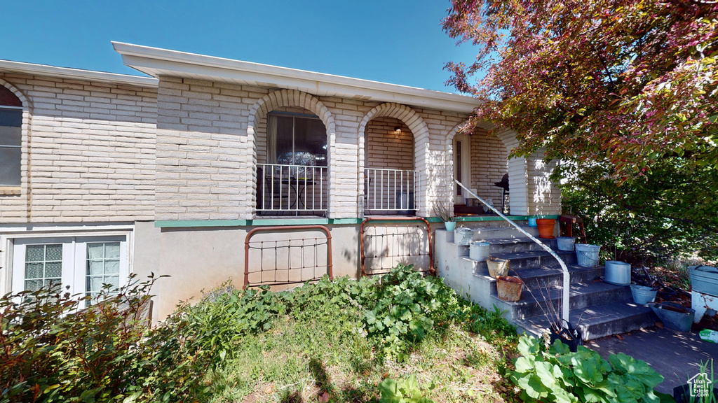 Property entrance featuring covered porch and brick siding