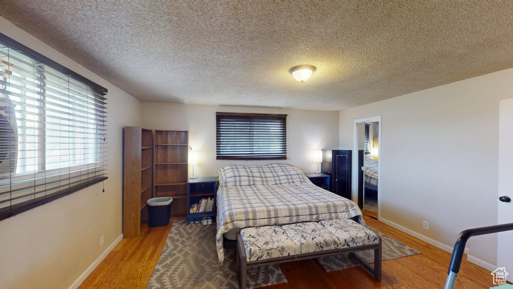 Bedroom with wood finished floors, multiple windows, and a textured ceiling