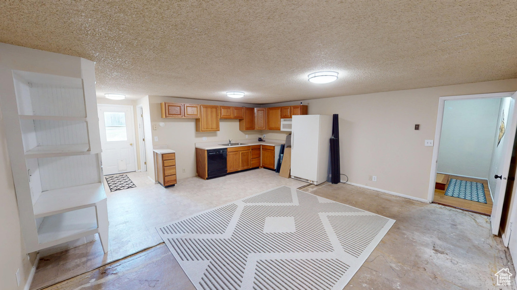 Kitchen featuring white appliances, light countertops, concrete flooring, and brown cabinets