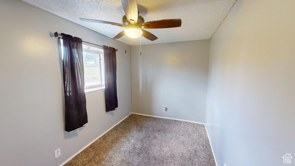 Empty room with a ceiling fan, carpet flooring, and a textured ceiling