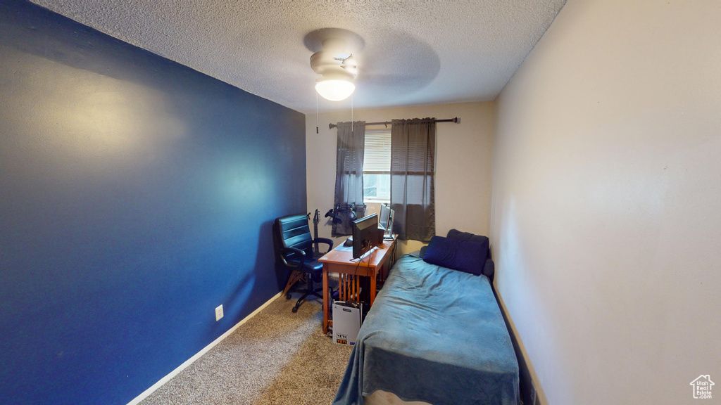 Carpeted home office with ceiling fan and a textured ceiling