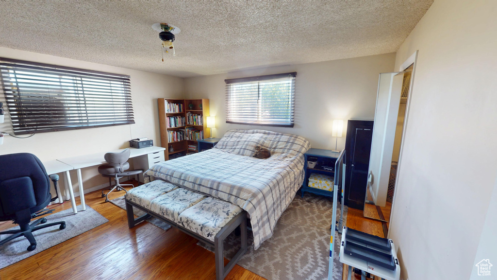 Bedroom with a textured ceiling and wood finished floors
