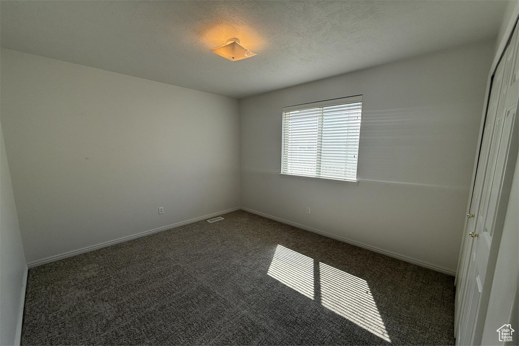 Unfurnished room with baseboards and dark colored carpet