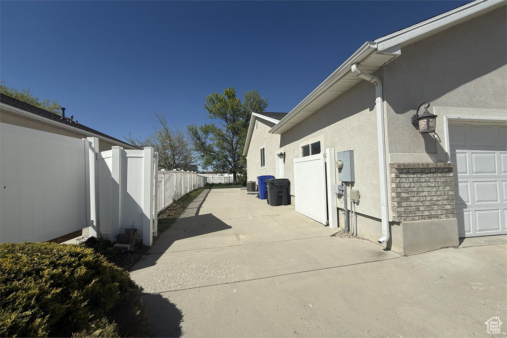 View of home's exterior with stucco siding, an attached garage, and fence