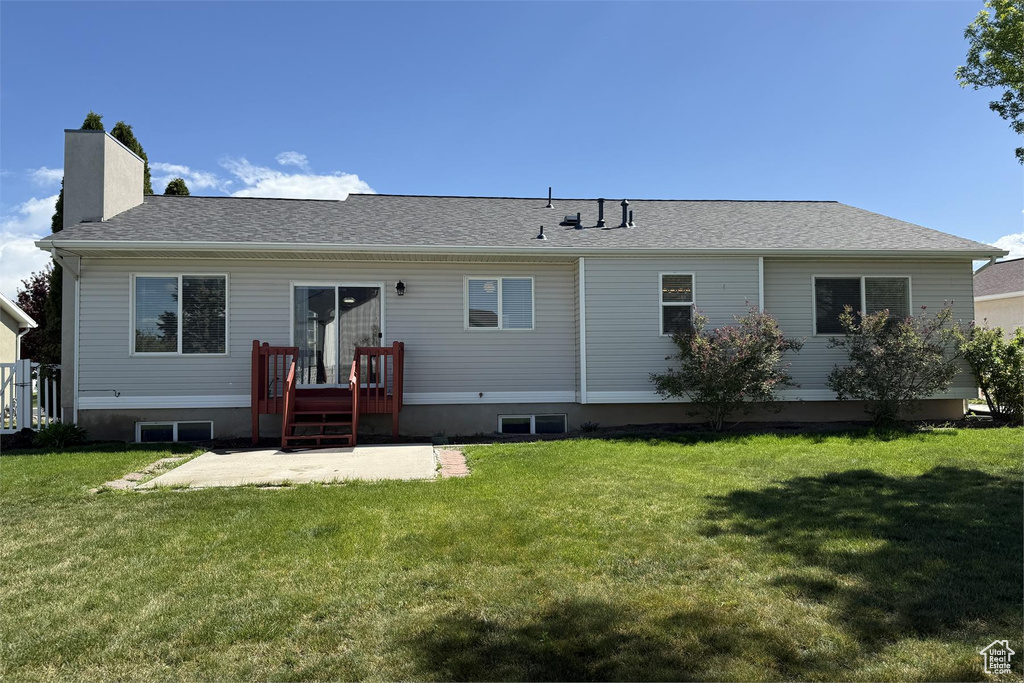 Back of house with a yard, a patio, a shingled roof, and a chimney