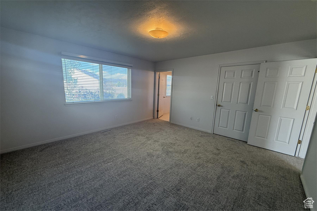Unfurnished bedroom with carpet floors, baseboards, and visible vents