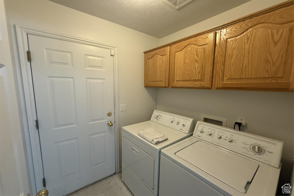 Laundry area with cabinet space, washing machine and dryer, visible vents, and marble finish floor