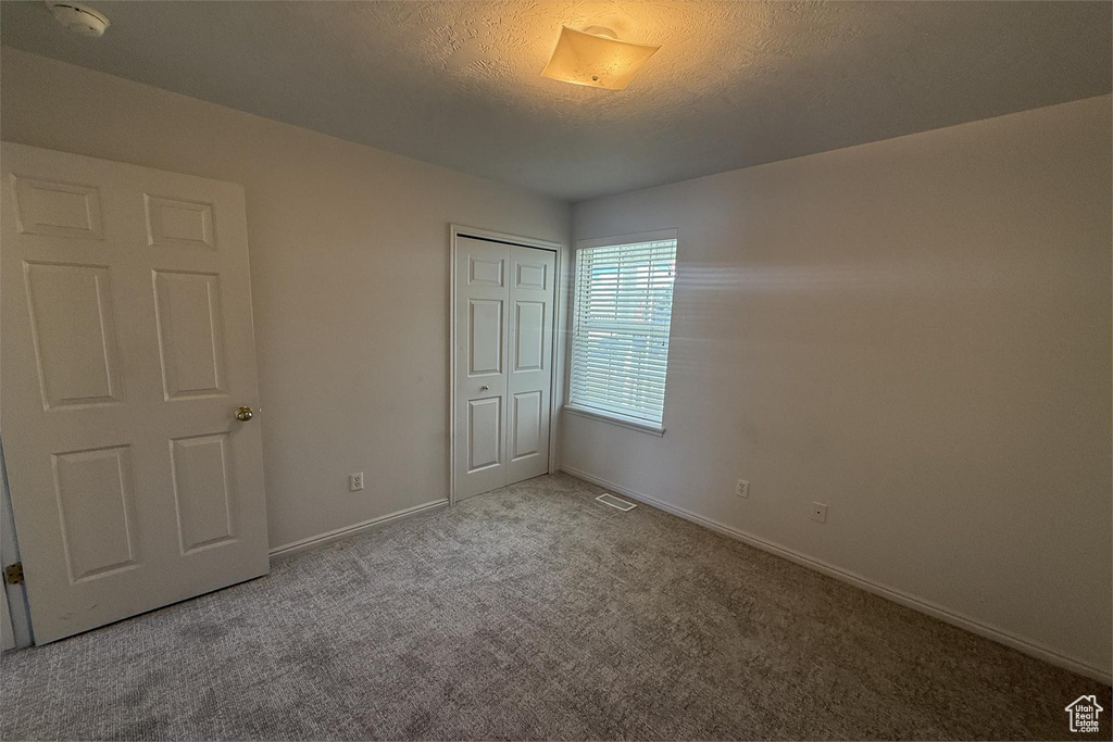 Unfurnished bedroom featuring baseboards, carpet flooring, a closet, and a textured ceiling