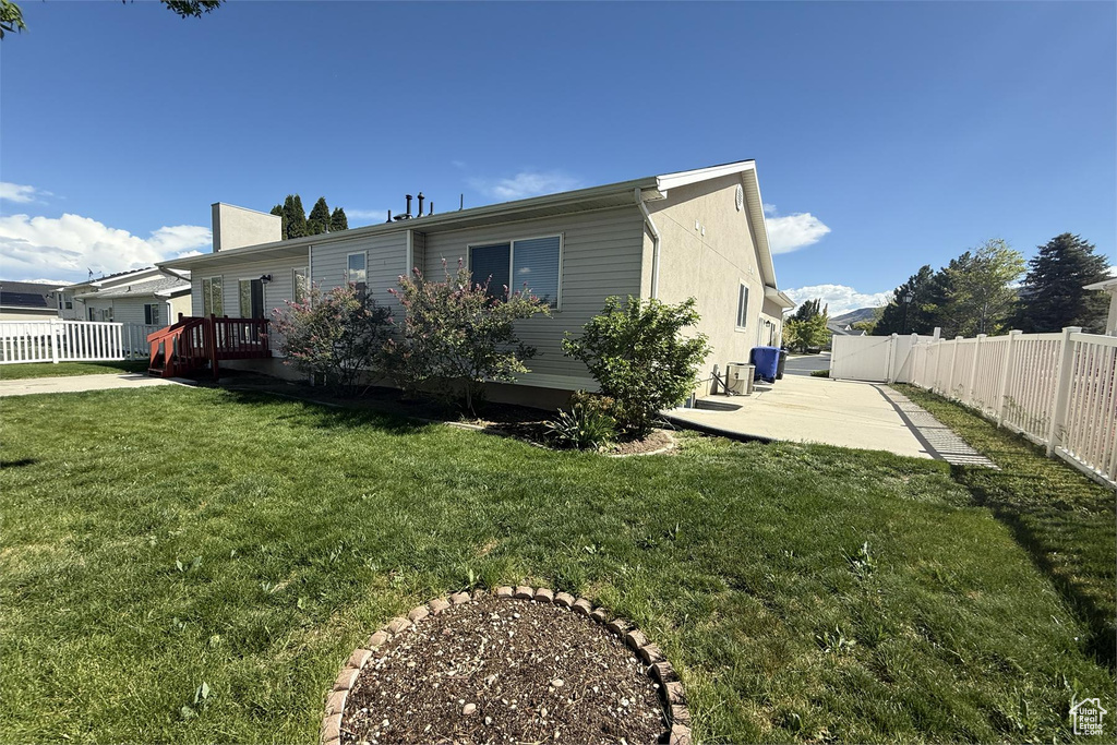 Back of house with a patio, a wooden deck, a lawn, and a fenced backyard
