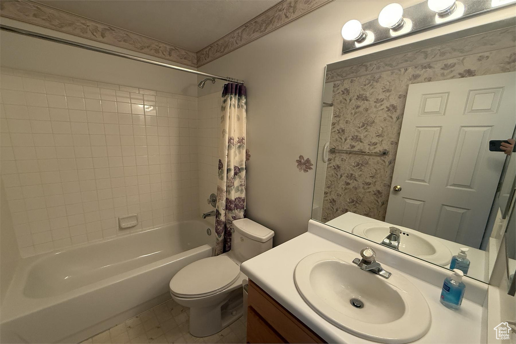 Full bathroom with vanity, shower / bathtub combination with curtain, and toilet