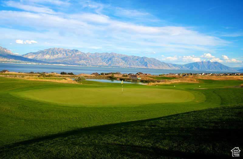 View of property's community featuring a putting area, a water and mountain view, and view of golf course