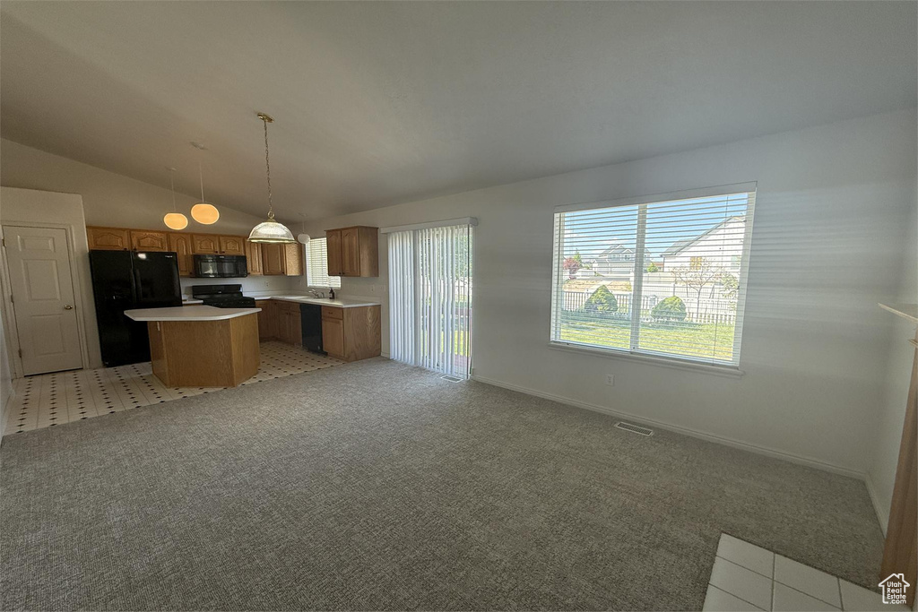 Kitchen featuring lofted ceiling, open floor plan, a kitchen island, black appliances, and light countertops
