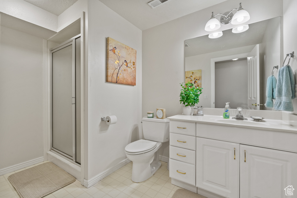 Bathroom featuring vanity, a stall shower, toilet, and visible vents