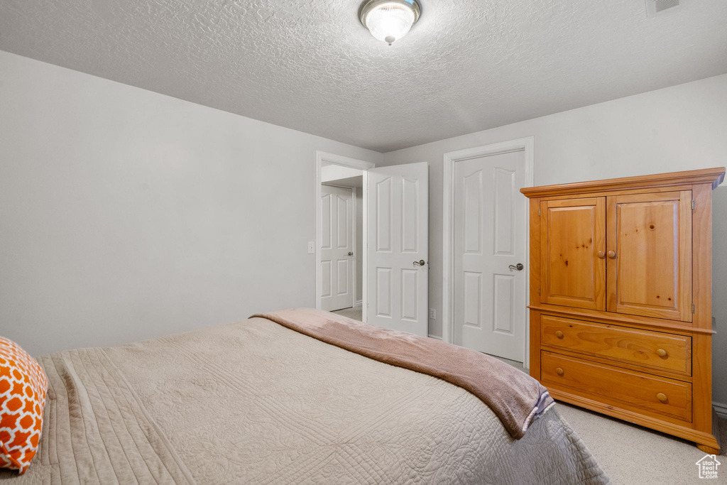 Bedroom with a textured ceiling and light colored carpet