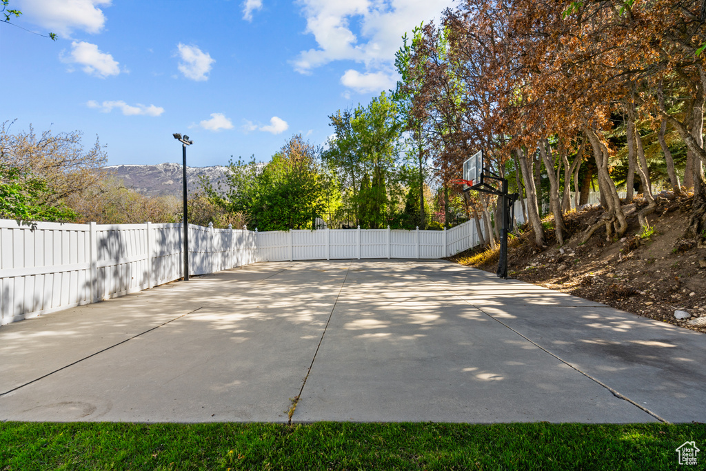 View of basketball court featuring fence, basketball hoop, and a mountain view