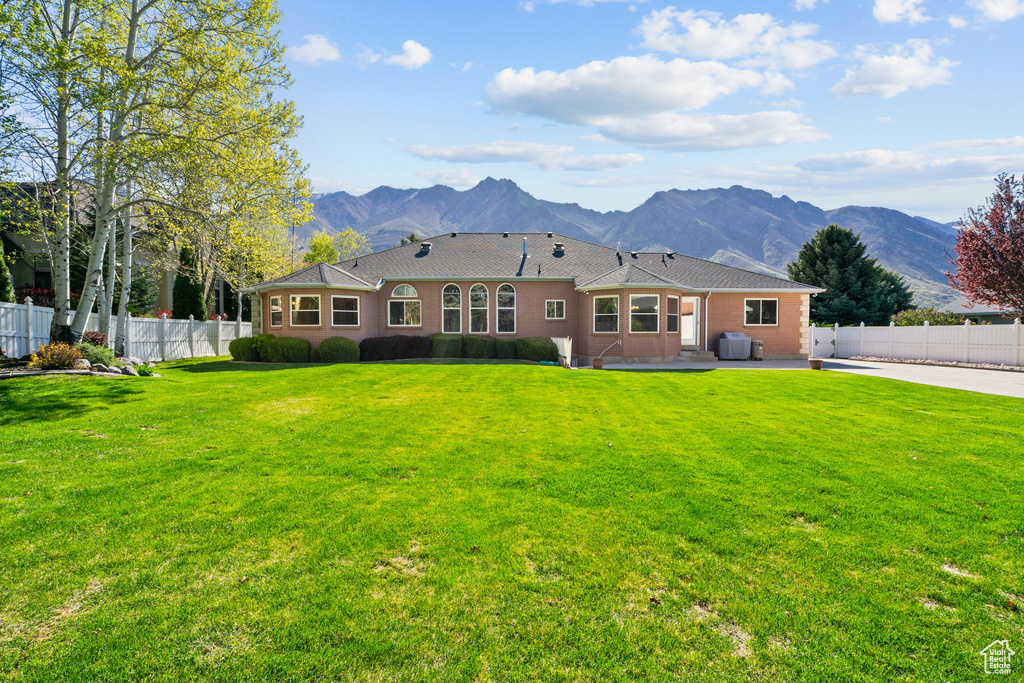 Rear view of property featuring fence, a mountain view, a yard, and a patio
