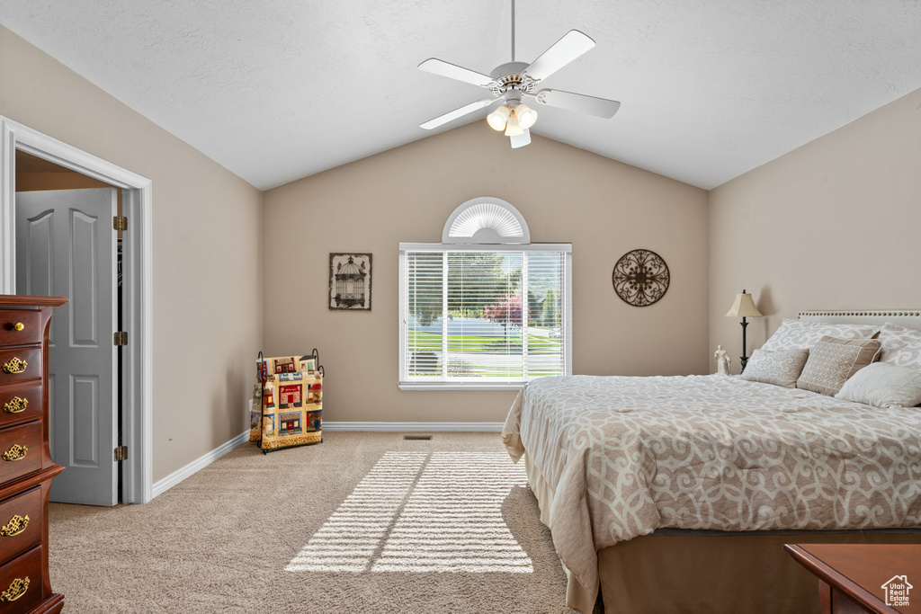 Bedroom featuring baseboards, a ceiling fan, vaulted ceiling, and light carpet