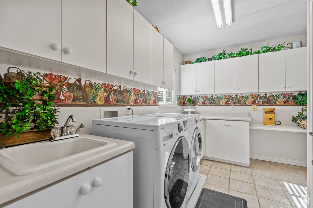 Washroom with a sink, cabinet space, independent washer and dryer, and light tile patterned floors