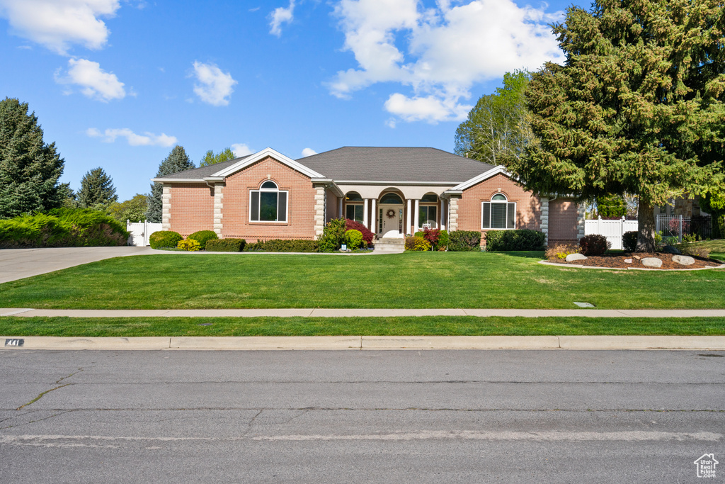 Single story home featuring fence, a front lawn, and brick siding