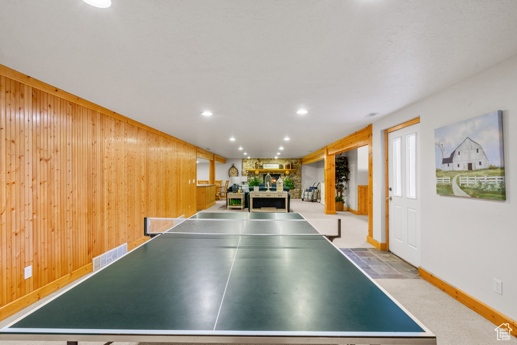 Recreation room featuring visible vents, a fireplace, baseboards, wooden walls, and recessed lighting