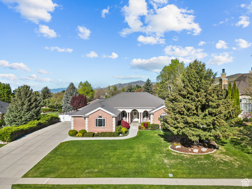 Single story home featuring a mountain view, driveway, a front lawn, and brick siding