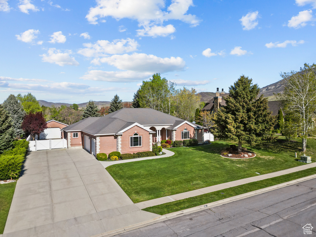 Ranch-style home featuring fence, a gate, a mountain view, and a front lawn