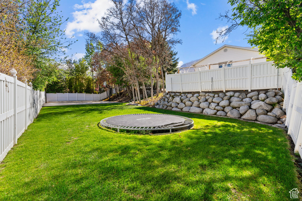 View of yard with a fenced backyard and a trampoline