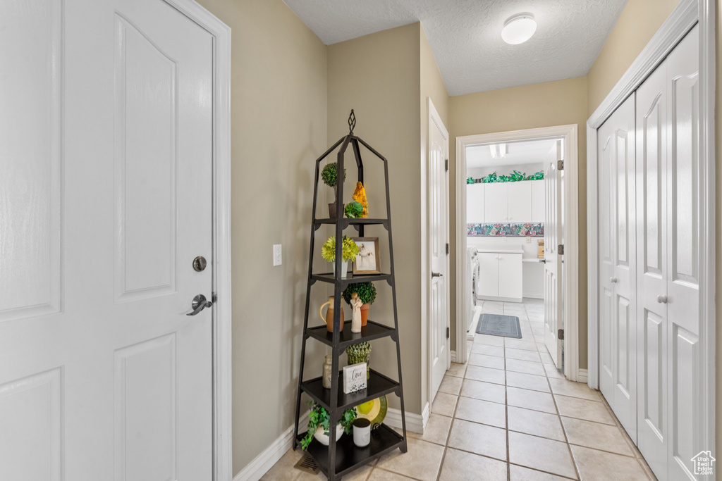 Interior space featuring light tile patterned floors, baseboards, and a textured ceiling