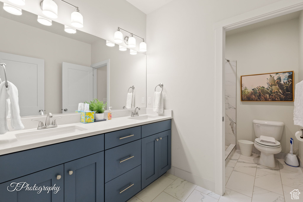 Full bath with a sink, double vanity, toilet, and marble finish floor