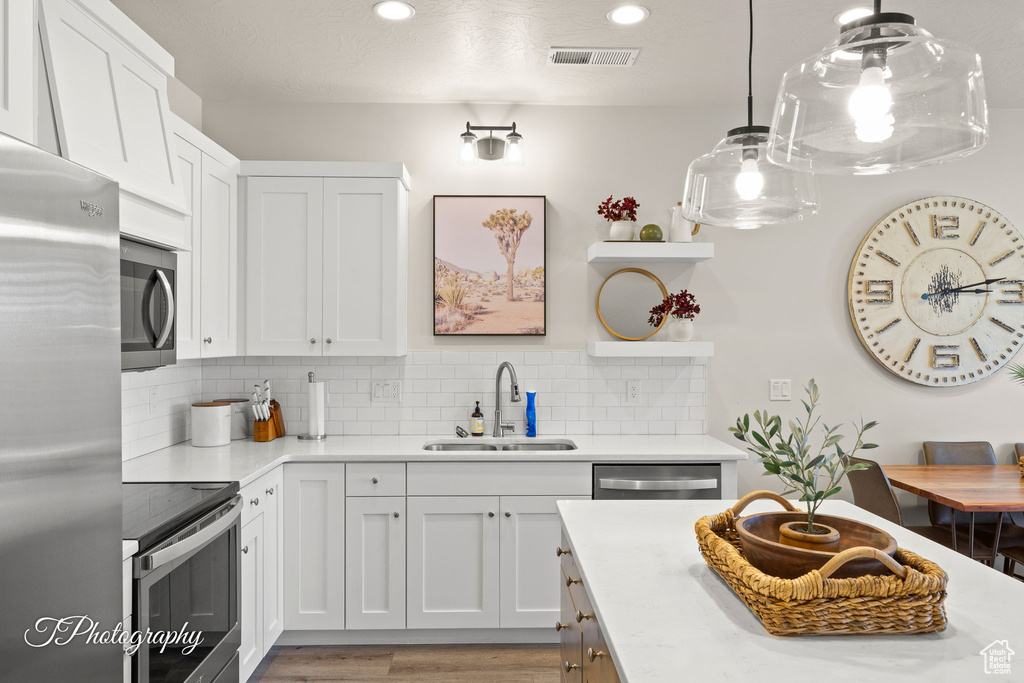 Kitchen with a sink, open shelves, light countertops, appliances with stainless steel finishes, and tasteful backsplash
