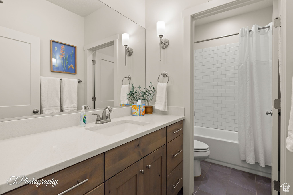 Bathroom featuring toilet, tile patterned floors, vanity, and shower / bath combination with curtain