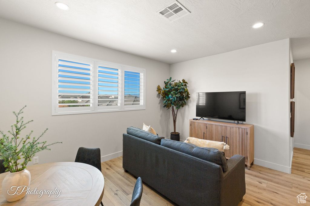 Living area with baseboards, light wood-type flooring, visible vents, and recessed lighting