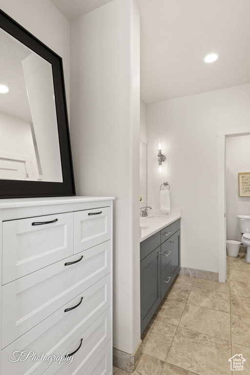 Bathroom featuring toilet, baseboards, vanity, and recessed lighting