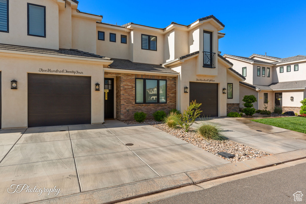 Townhome / multi-family property featuring driveway, stucco siding, and a garage
