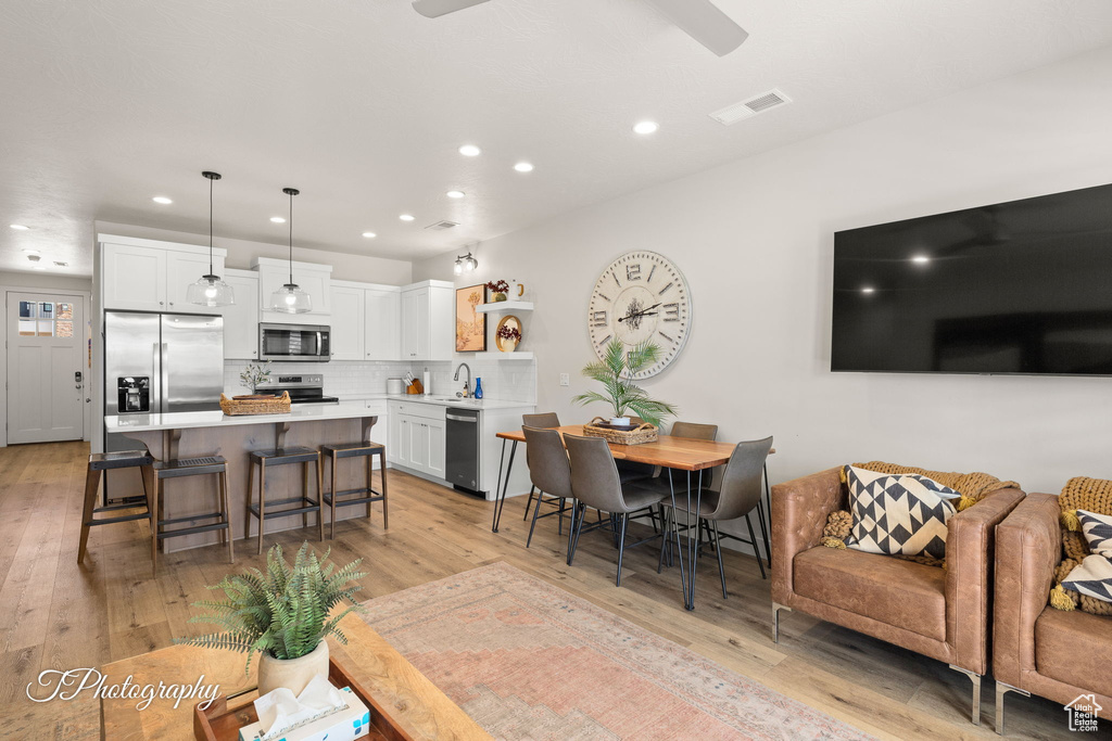 Living room with light wood-type flooring, visible vents, a ceiling fan, and recessed lighting