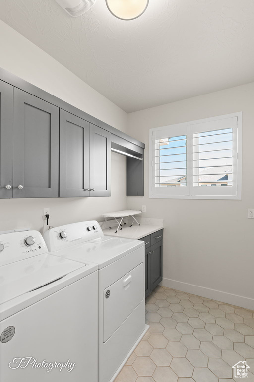 Clothes washing area with washing machine and clothes dryer, baseboards, and cabinet space