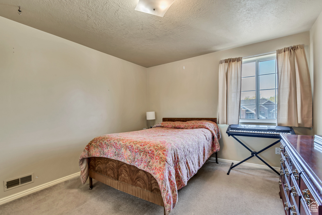 Bedroom with carpet, a textured ceiling, and visible vents
