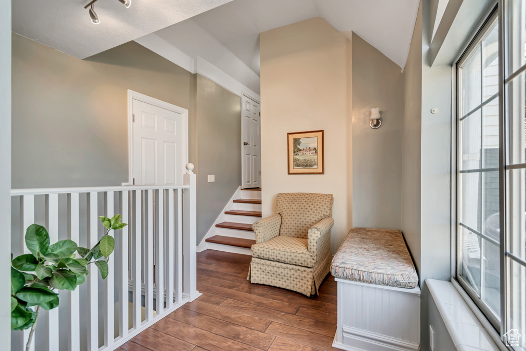 Living area with baseboards, wood-type flooring, and vaulted ceiling