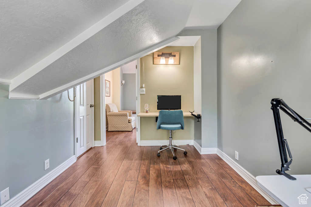 Office area featuring lofted ceiling, baseboards, and wood-type flooring